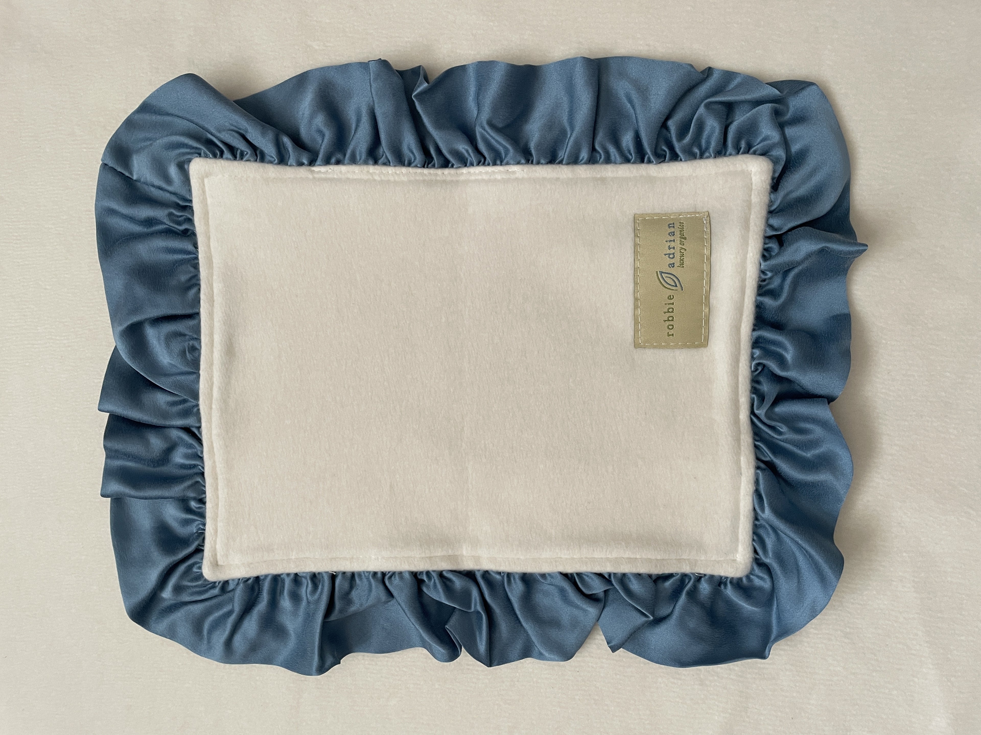 Lovey with blue silk ruffle on organic cotton fleece, flat view with label