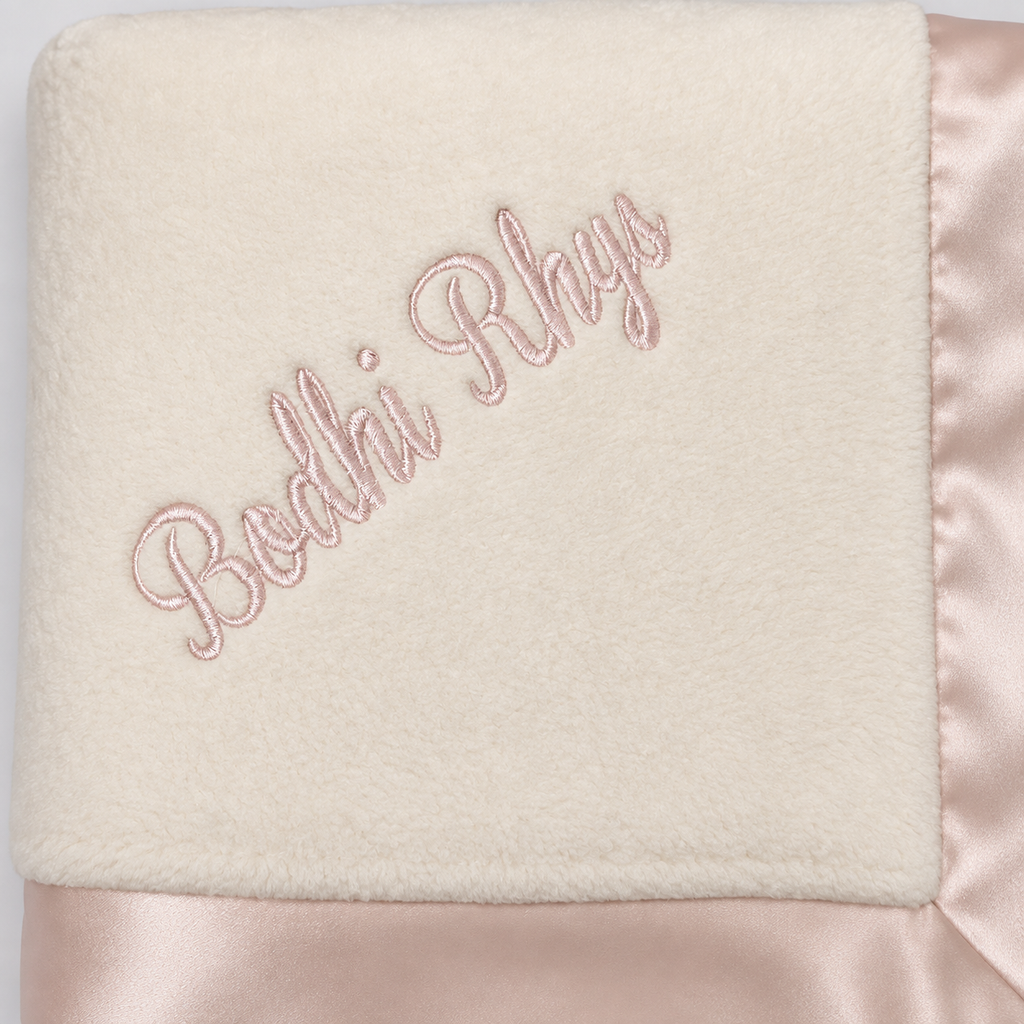 Pink name embroidery on a cream organic cotton blanket