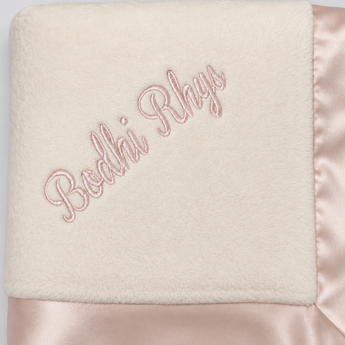 Pink name embroidery on a cream organic cotton blanket