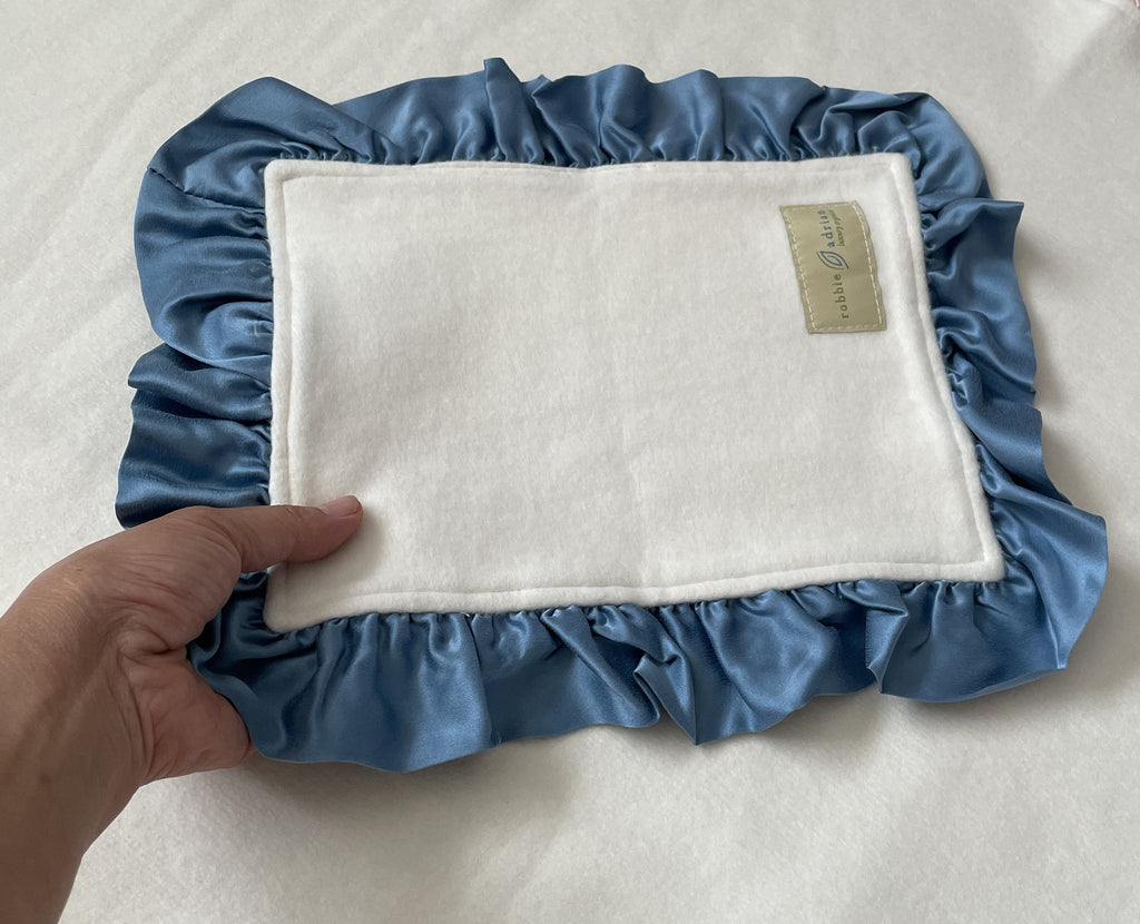 Lovey with blue silk ruffle held in hand for scale
