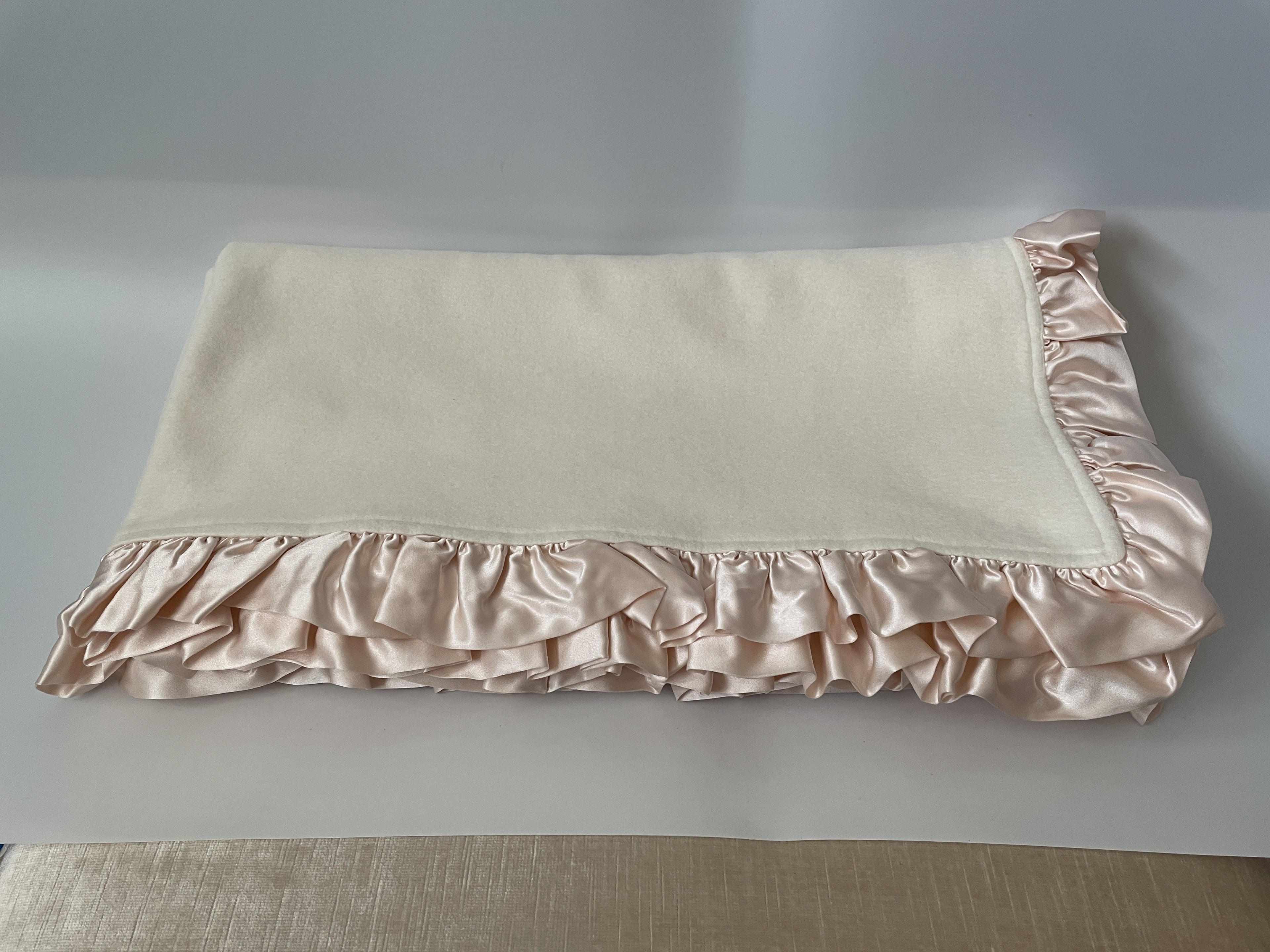 Organic cotton fleece blanket with pink silk ruffle, folded with ruffle cascade