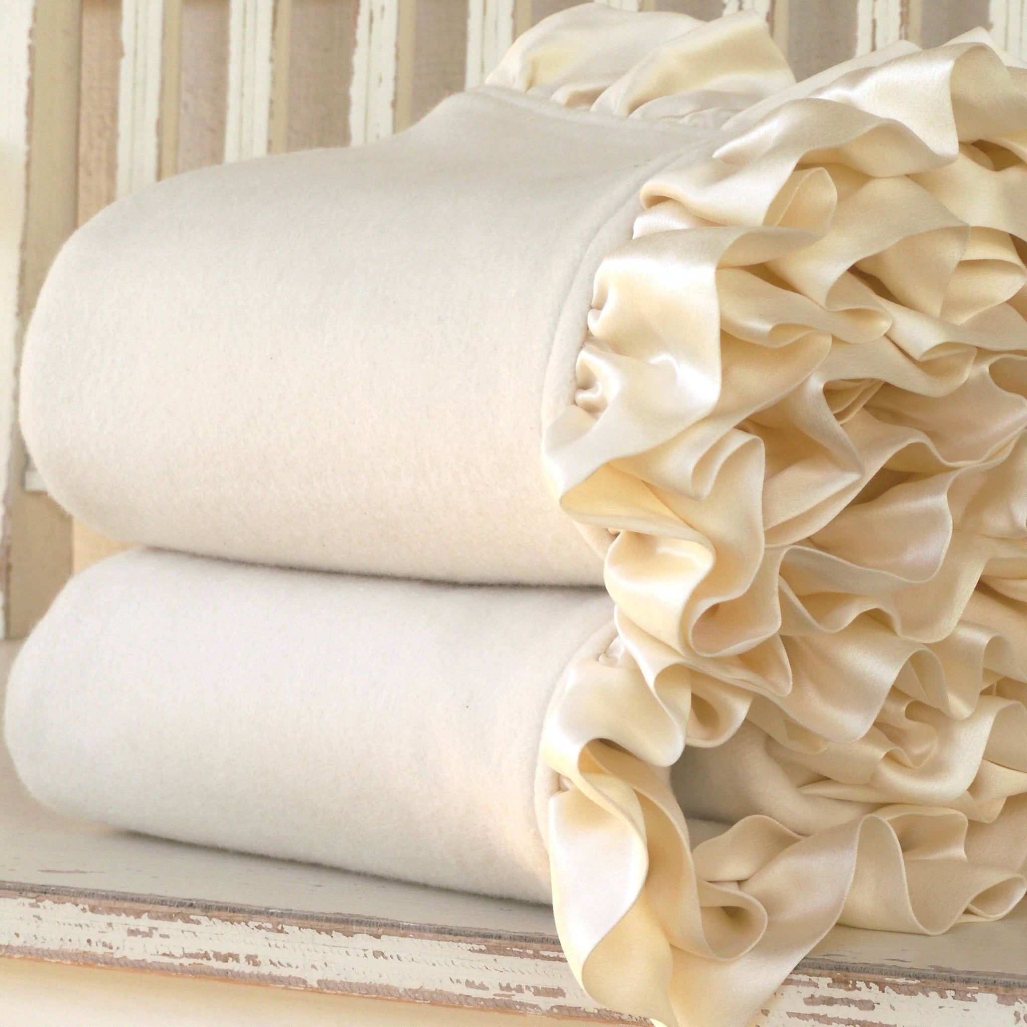 Cream organic cotton fleece baby blankets with silk charmeuse ruffle, folded and stacked