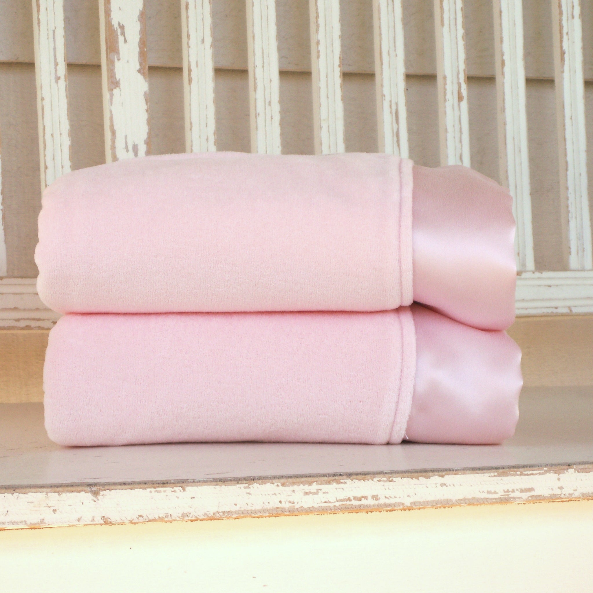 Pink organic cotton fleece baby blankets with straight silk charmeuse trim, folded